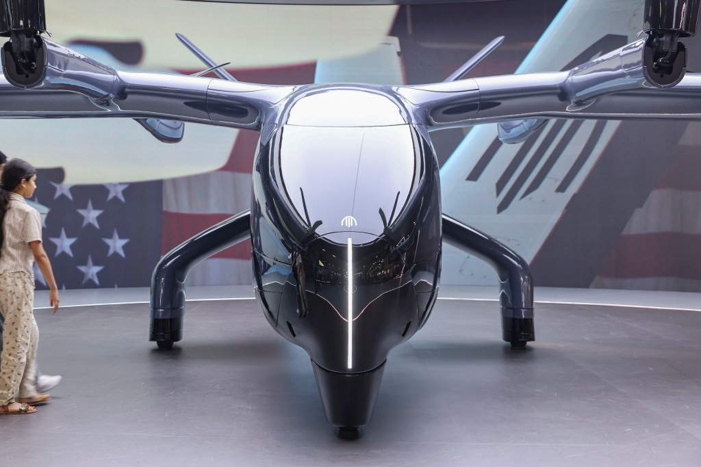 Visitors take photographs of the Archer Midnight electric vertical takeoff and landing aircraft eVTOL with the futuristic design as displayed inside the exhibition hall during the Paris Air Show 2025 at Le Bourget Airport. The Archer Midnight with registration tail number N302AX, developed by California-based Archer Aviation, is designed as a piloted and four passenger air taxi aimed at reducing urban congestion through sustainable electric air mobility. The Midnight aircraft's first test flight outside the United States took place in July 2025 at Al Bateen Executive Airport in Abu Dhabi, where it was evaluated under local environmental conditions as part of preparations for regional certification aiming to the usage of affordable air taxi transportation. Paris Air Show, one of the oldest and largest in the world aerospace events, gathers global industry leaders to showcase the latest advancements in aviation, defense, and space technology. Le Bourget, France on June 22, 2025 (Photo by Nicolas Economou/NurPhoto via Getty Images)